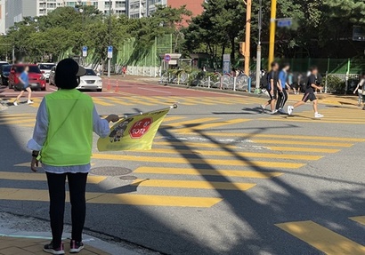 학교 앞 건널목에서 녹색어머니 활동을 하는 학부모가 교통 안전 지도 활동을 하고 있다. 사진=박해나 기자